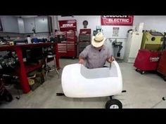 a man in a garage working on a white chair that is shaped like a boat