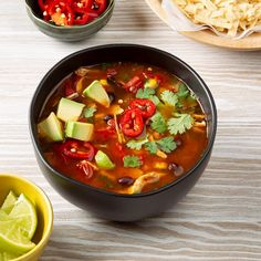 a bowl of mexican soup with tortilla chips and limes on the side