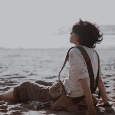 a person sitting in the sand with a backpack