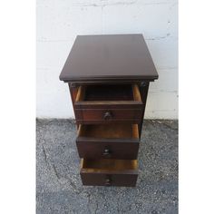 a small wooden table with three drawers on one side and an open drawer on the other