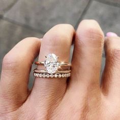 a woman's hand with two wedding rings on top of her finger and the ring has a diamond in it