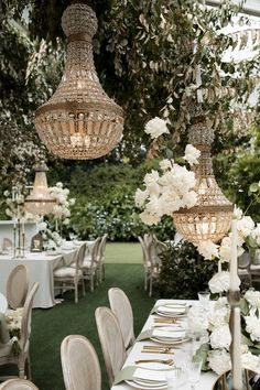 an outdoor dining area with chandeliers and tables set up for a formal function