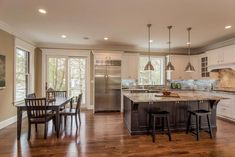 a large kitchen with white cabinets and wooden floors