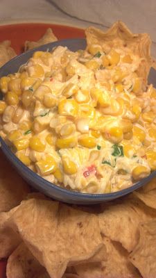 a blue bowl filled with corn salad and tortilla chips on top of a plate