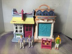 two dolls are standing next to each other in front of a doll house and store