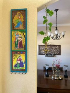 a wall hanging with paintings on it next to a dining room table