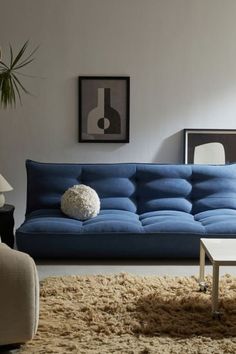 a living room with a blue couch and coffee table in front of a white wall