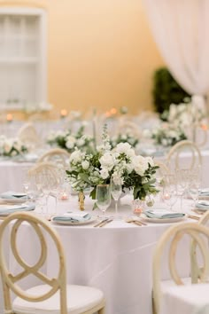 the table is set with white flowers and place settings