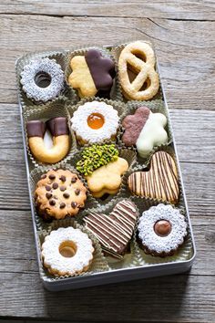 a box filled with assorted pastries on top of a wooden table