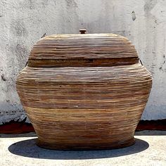 a large basket sitting on the ground next to a white wall with a brown lid