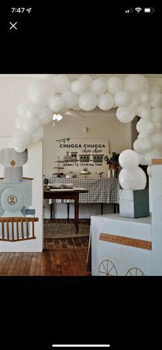 a room filled with white balloons and decorations on the ceiling next to a dining table