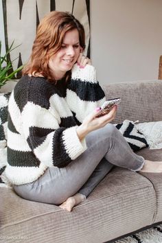 a woman sitting on top of a couch holding a cell phone