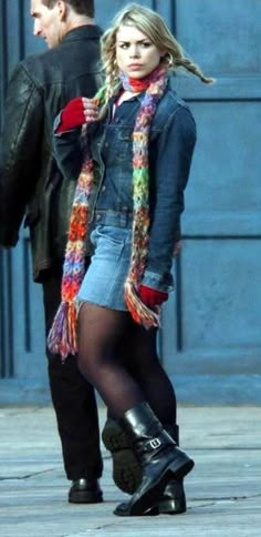 a woman in tights and boots is walking down the street with her scarf around her neck