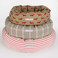 three dog beds stacked on top of each other in different colors and patterns, one with a red dachshund print