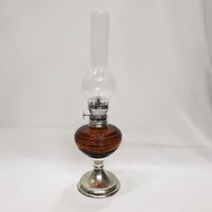 an old fashioned oil lamp with a wooden base and clear glass bulb sitting on a white background