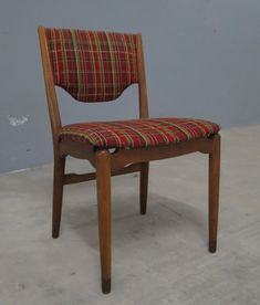 a wooden chair with a plaid seat pad on the back and sides, against a gray wall