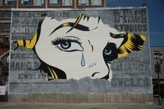 a large mural on the side of a building depicting a woman's face with tears