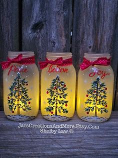 three mason jars with christmas trees painted on them