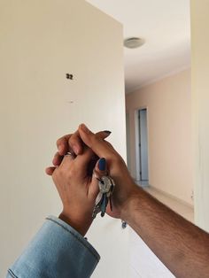 two people holding keys in their hands while they are looking at the wall behind them