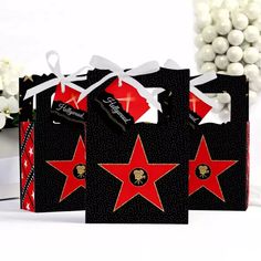 three bags with red stars on them are sitting next to some white flowers and balls