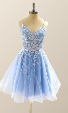 A bold, blue-hued dress crafted from Tulle - adorned with delicate white florals. Features include a A-line silhouette, spaghetti straps, a V neckline, and a lace-up back. Hits just above the knee. Blue Tulle Dress With Spaghetti Straps, Blue Spaghetti Strap Dress For Wedding, Spring Prom Dress With Delicate Straps, Light Blue Spaghetti Strap Wedding Dress, Blue Sleeveless Dress With Delicate Straps, Blue Party Dress With Delicate Straps, Blue Lace Bodice Summer Dress, Blue Dresses With Lace-up Back And Sweetheart Neckline, Blue Lace Bodice Dress For Summer