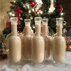 six empty wine bottles sitting on a table in front of a christmas tree with lights