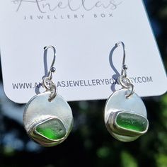 These stunning green sea glass earrings each feature a similar in size and colour piece of sea glass. The earrings themselves are round in shape and the sea glass pieces have been set into each earring for a beautiful finish.  They are sure to be a hit with any lovers of sea glass jewellery and dangle earrings. The earrings can be worn for everyday wear or kept for special occasions. Each pair are completely unique as no piece of sea glass is the same.  These stunning dangly earrings will come s Handmade Sea Glass Green Earrings, Green Recycled Glass Dangle Earrings, Sea Glass Teardrop Earrings As Gift, Green Dangle Earrings In Recycled Glass, Green Dangle Earrings With Recycled Glass, Teardrop Sea Glass Earrings For Gift, Green Sea Glass Earrings For Gift, Sea Glass Dangle Earrings Gift, Green Sea Glass Earrings With Ear Wire