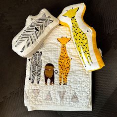 the baby's bib is decorated with different animal designs on it, including giraffes and zebras