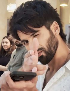 a man holding a cell phone in his right hand and pointing at it with both hands