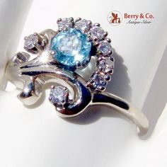 "Vintage Aquamarine Floral Design Ring 14 K (.585) White Gold, Diamond Accents. This beautiful ring is a size 10, it is 9/16\" wide and weighs 5 grams. The stone is 5 mm in diameter. [nb1020]" Exquisite Hallmarked Gemstones For Anniversary, Hallmarked Round Cut Diamond Topaz Ring, Fine Jewelry Gemstones With Polished Finish For Anniversary, Fine Jewelry Gemstones For Anniversary, Elegant Multi-stone Blue Topaz Rings, Anniversary Multi-stone Blue Topaz Rings, Anniversary White Gold Multi-stone Topaz Ring, Elegant Blue Topaz Multi-stone Rings, Blue Topaz Multi-stone Rings For Anniversary