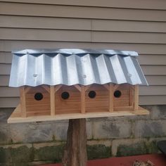 a wooden birdhouse with four birds on it's roof