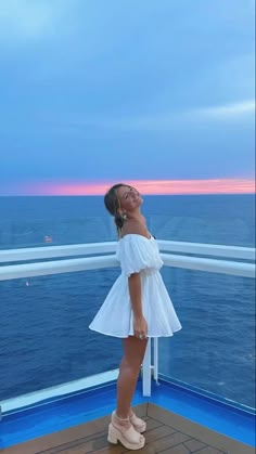 a woman standing on the deck of a cruise ship looking up at the sky and smiling