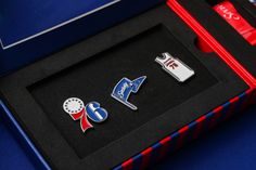 two lapel pins in a black box on a blue tablecloth with red and white trim