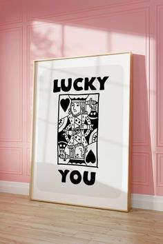 an art print with the words lucky you in black and white on a pink wall