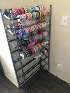 there is a rack with many different colored ribbons on the wall and in front of it