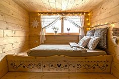 a bed sitting inside of a wooden room next to a window with lights on it