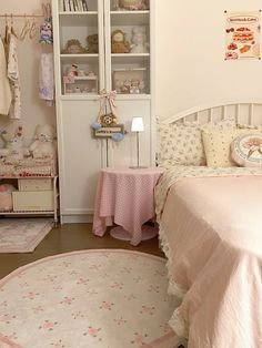 a white bed sitting next to a pink rug on top of a wooden floor