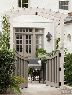 a white house with an outdoor dining table and potted plants on the front porch