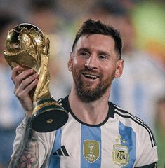 a close up of a person holding a soccer ball and trophy in front of his face