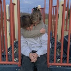 two children are sitting on a playground play structure with their arms around each other's shoulders