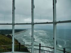 the view from an open window looking out at the ocean and land beyond it is cloudy