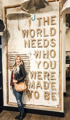 a woman standing in front of a sign that says the world needs who you were made to be