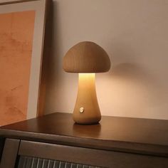 a mushroom shaped lamp sitting on top of a wooden table next to a framed painting