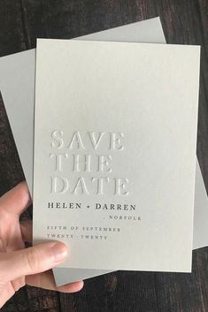 someone holding up some white cards with the words save the date written on them in silver foil