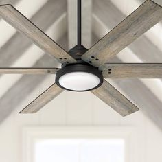 a ceiling fan with wooden blades in a room