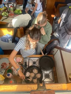 three people are cooking in a kitchen with pots and pans on the stove top