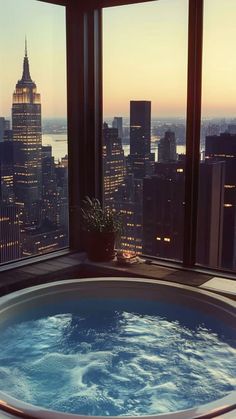 a large hot tub sitting in front of a window overlooking a cityscape at sunset