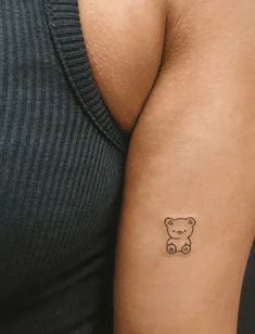 a person with a small bear tattoo on their left arm and the other arm behind him