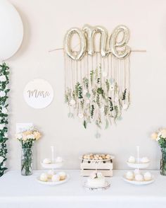 a table topped with lots of cakes and cupcakes next to balloons that say one