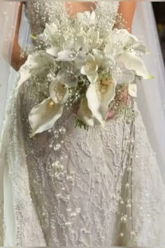 a woman in a wedding dress holding a bridal bouquet with white orchids and baby's breath